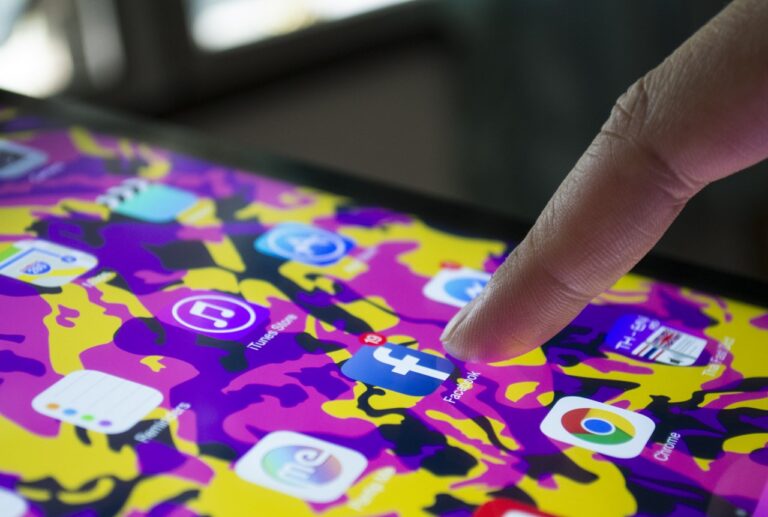 Image of a woman touching the Facebook icon on a smartphone